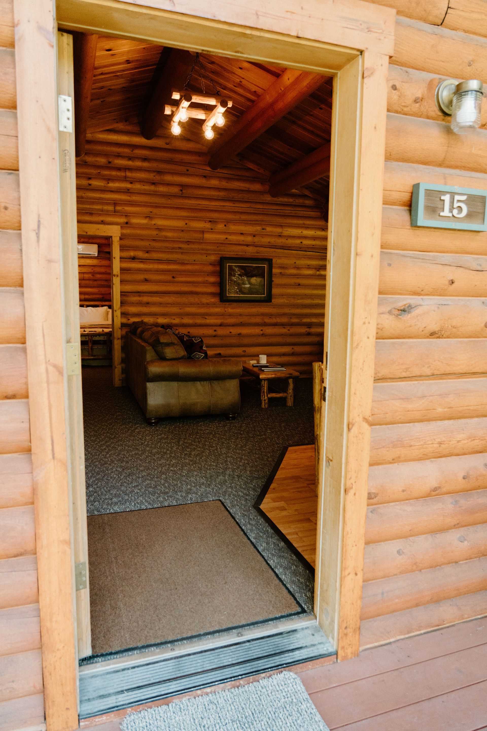 The door is open to a living room in a log cabin.