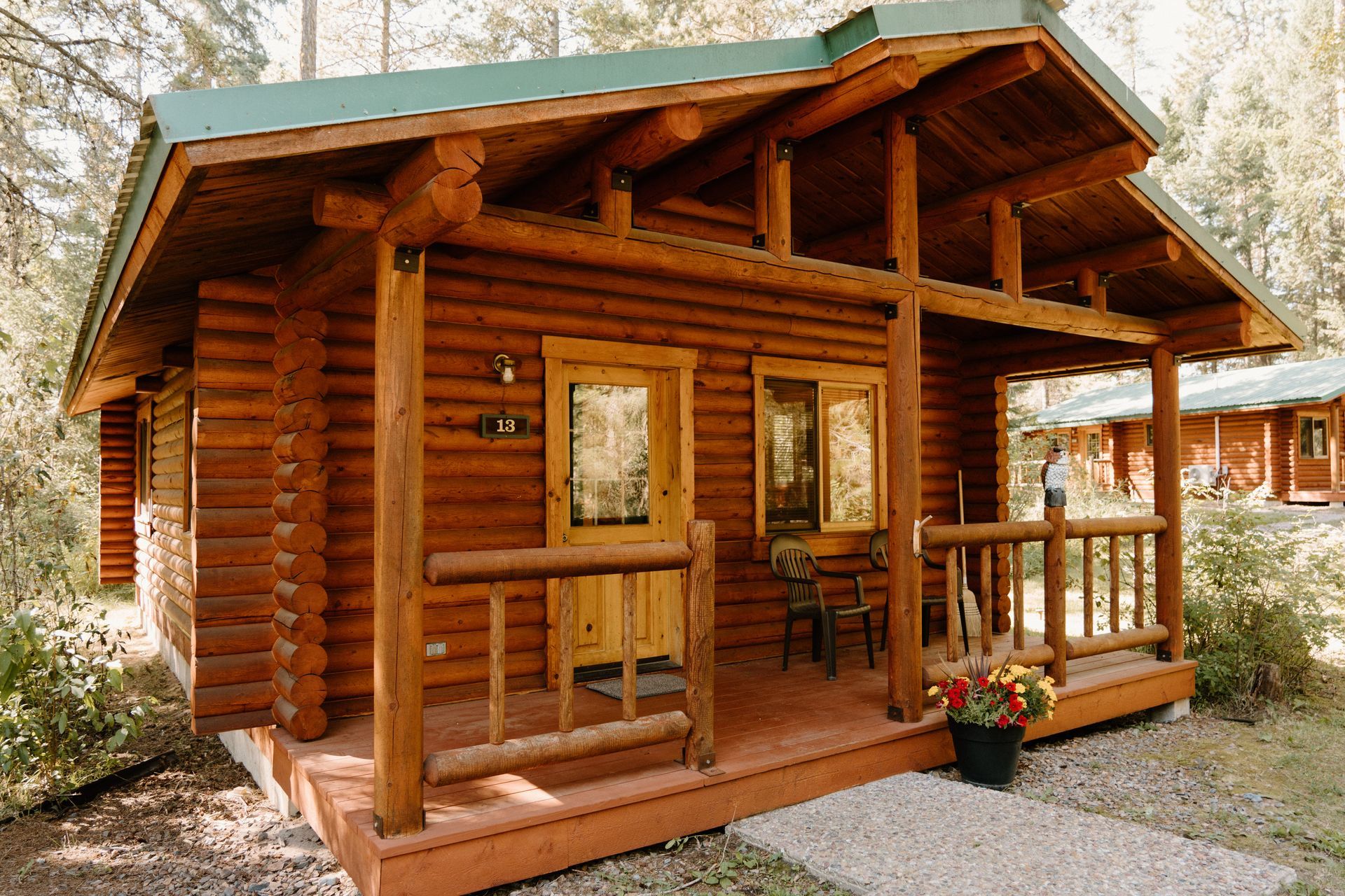 A small log cabin with a green roof and a porch