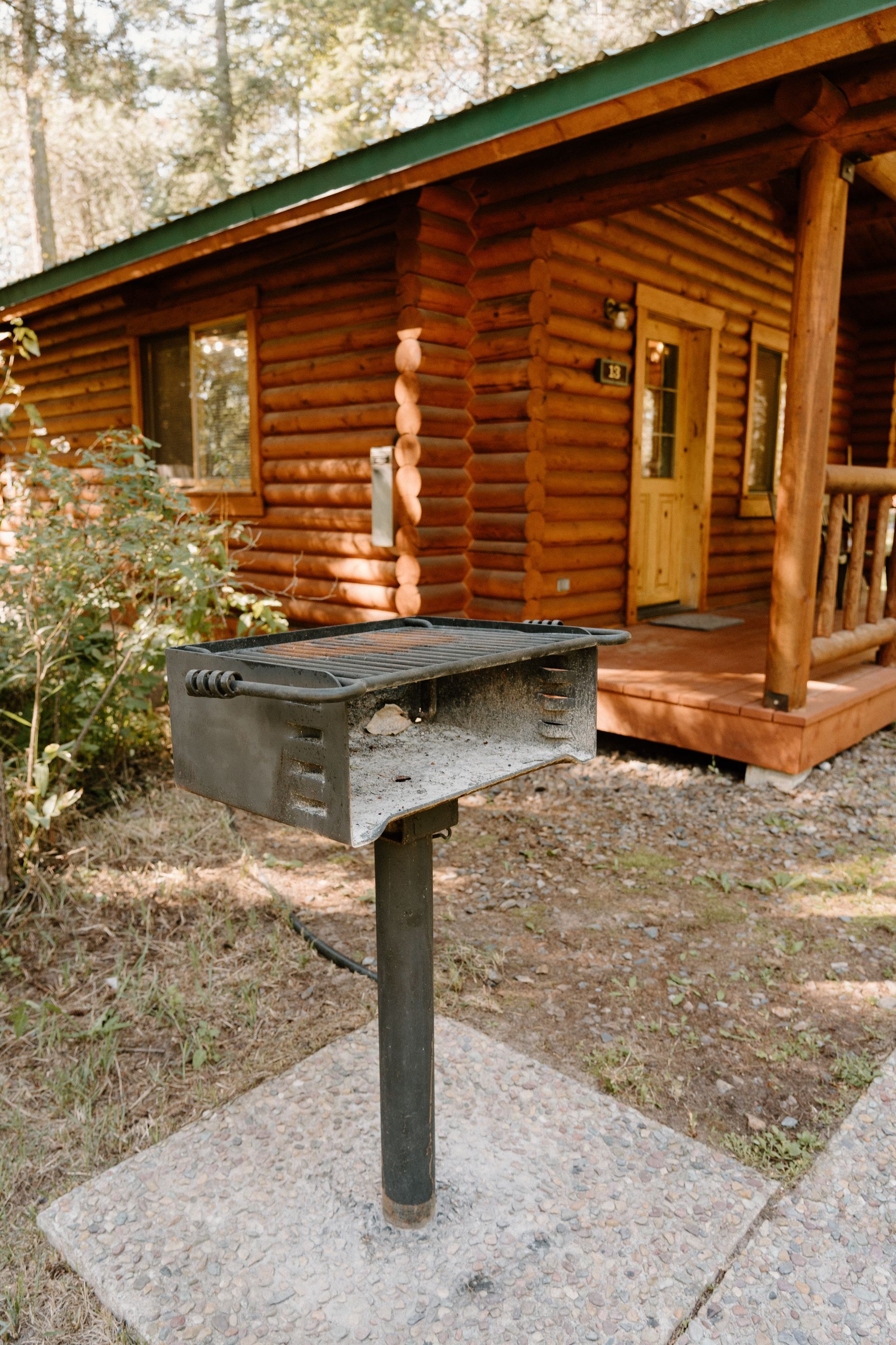 A grill is sitting in front of a log cabin.