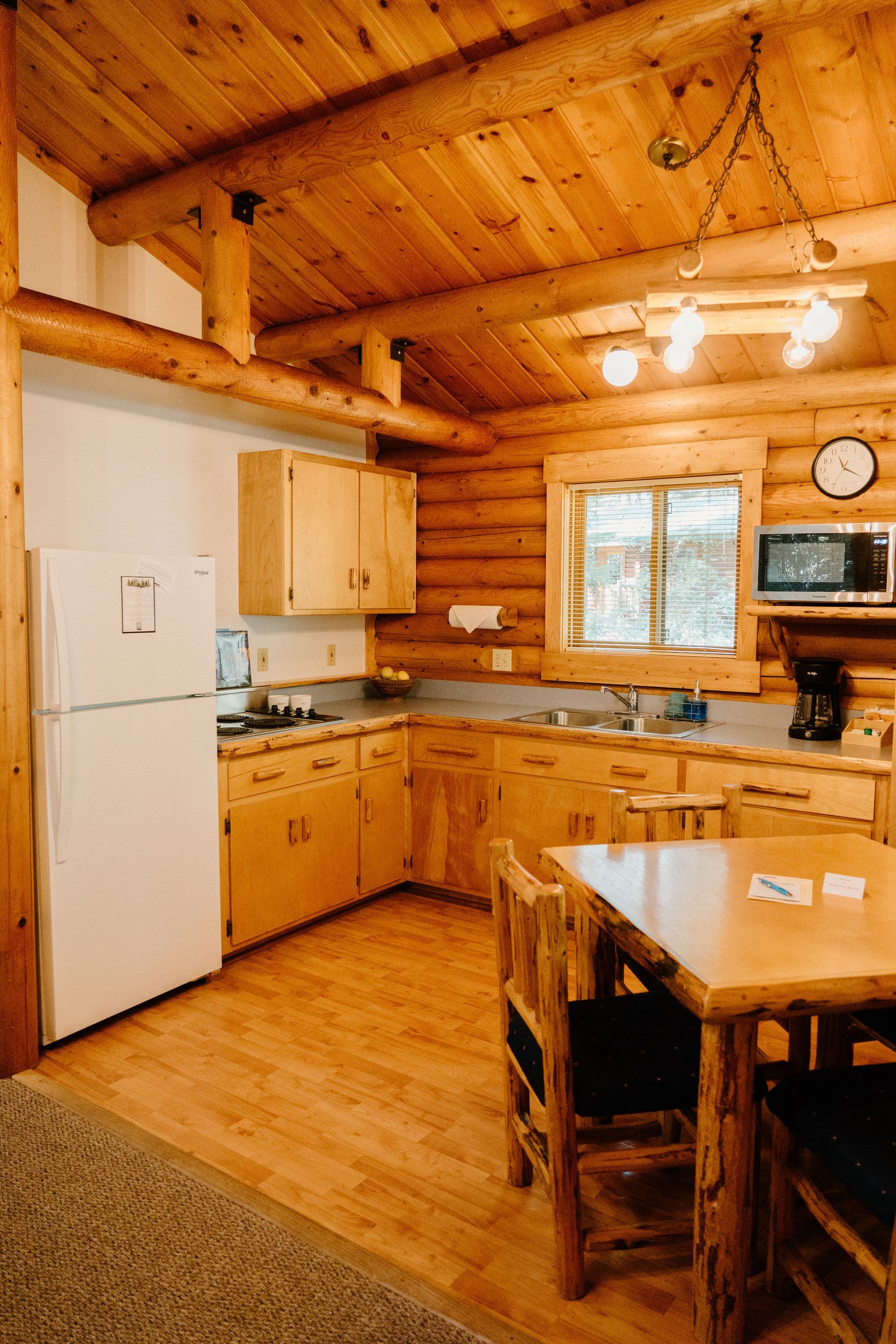 A kitchen in a log cabin with a table and chairs.