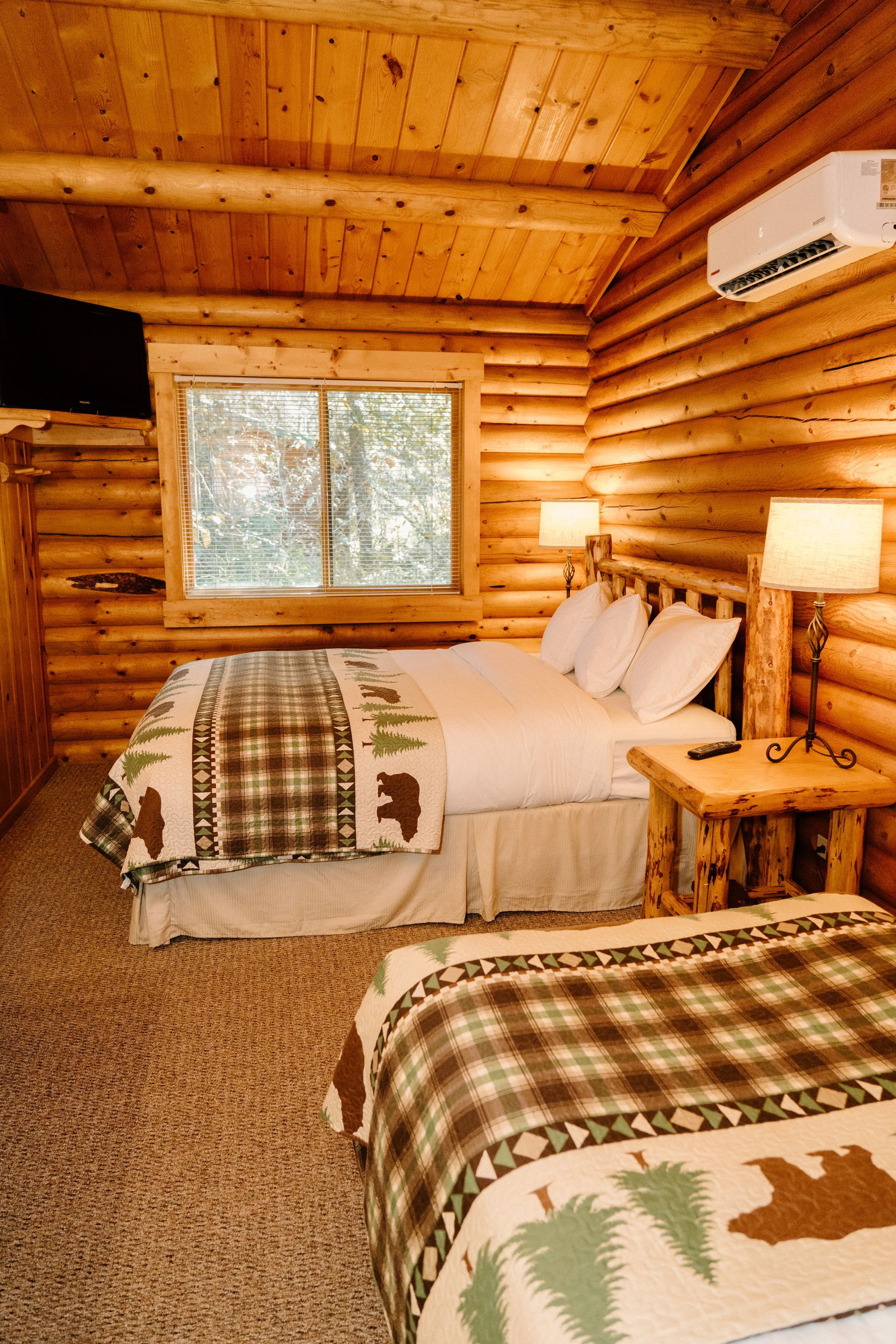 A bedroom in a log cabin with two beds and a window.