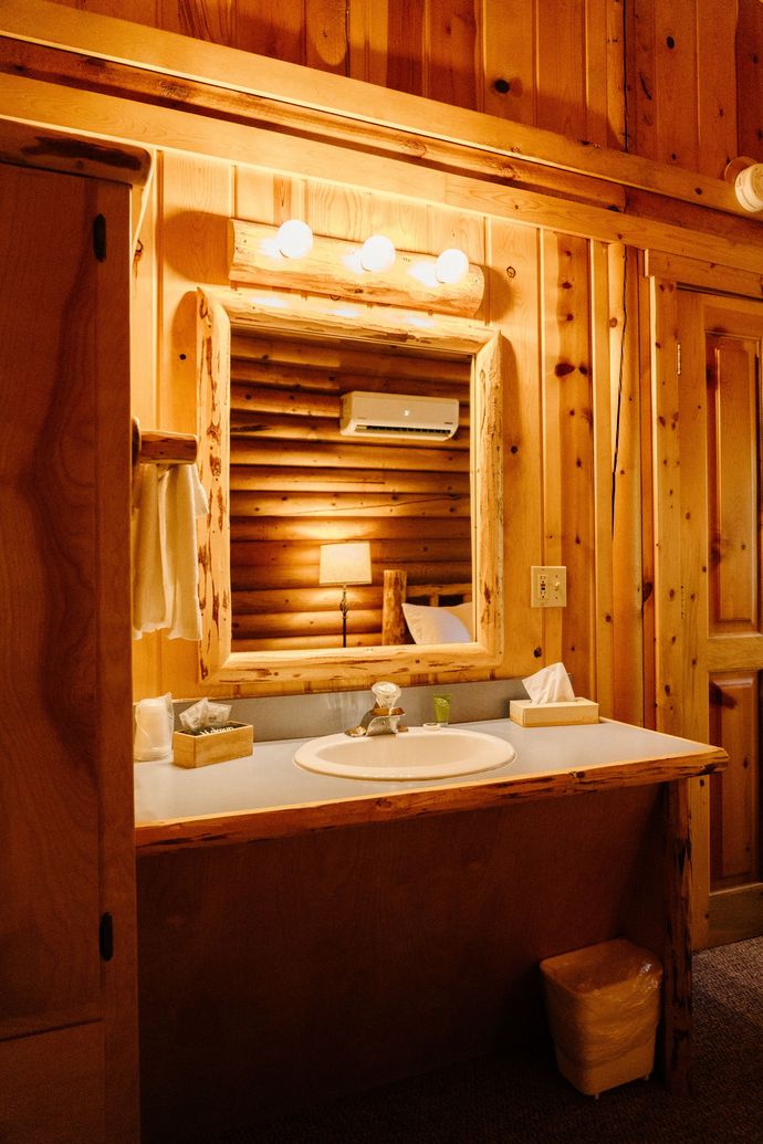 A bathroom in a log cabin with a sink and mirror