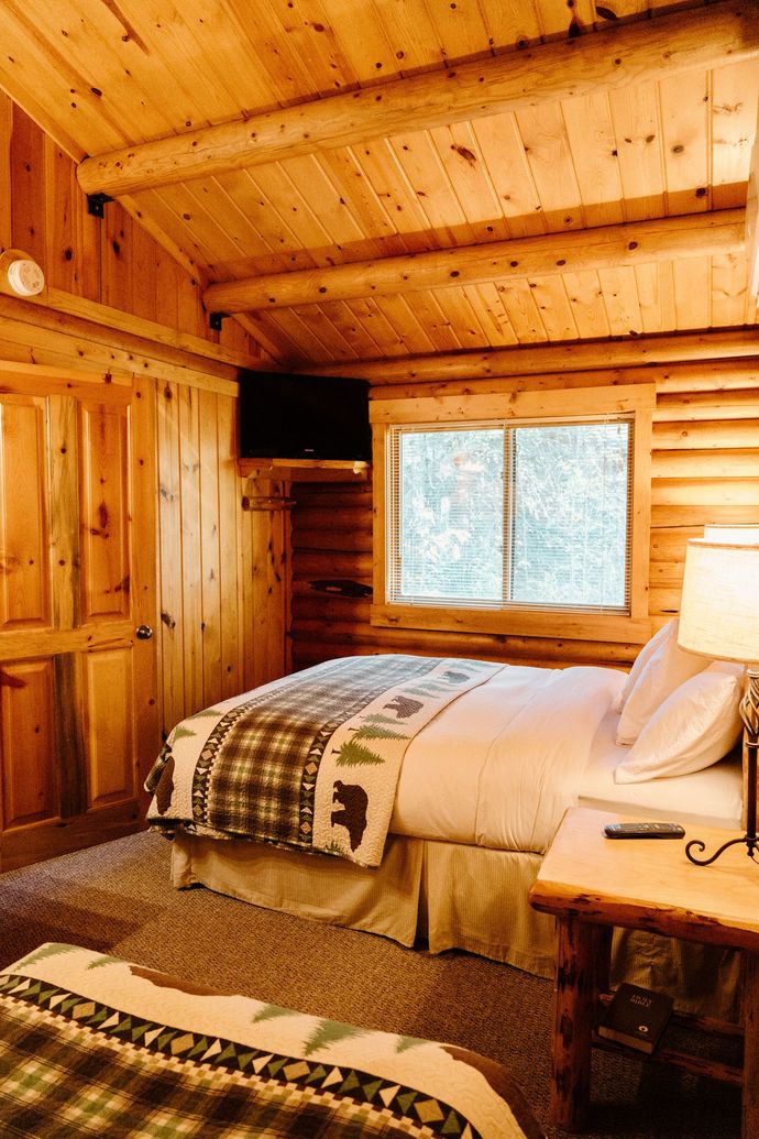 A bedroom in a log cabin with two beds and a television.