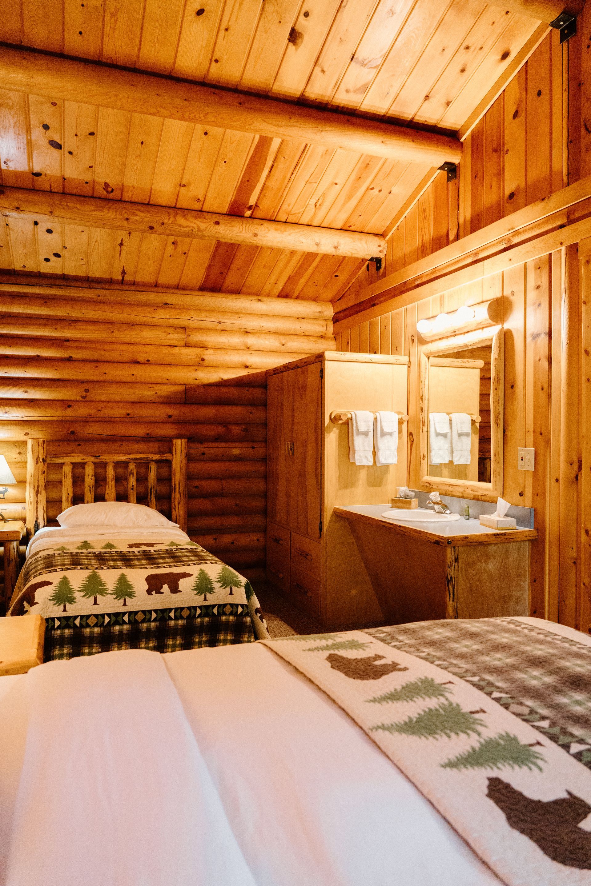 A bedroom in a log cabin with two beds and a sink