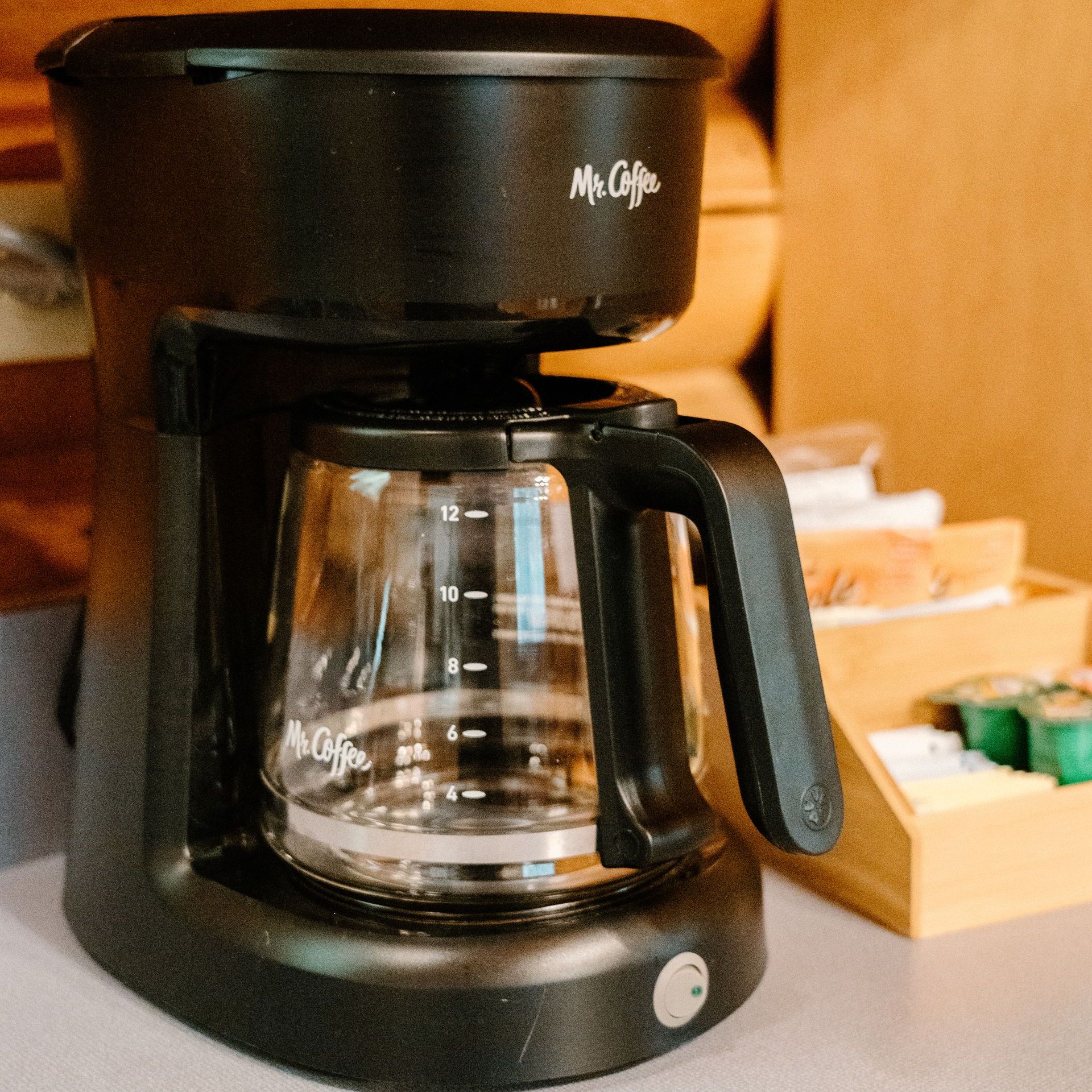 A black coffee maker is sitting on a counter in a kitchen.