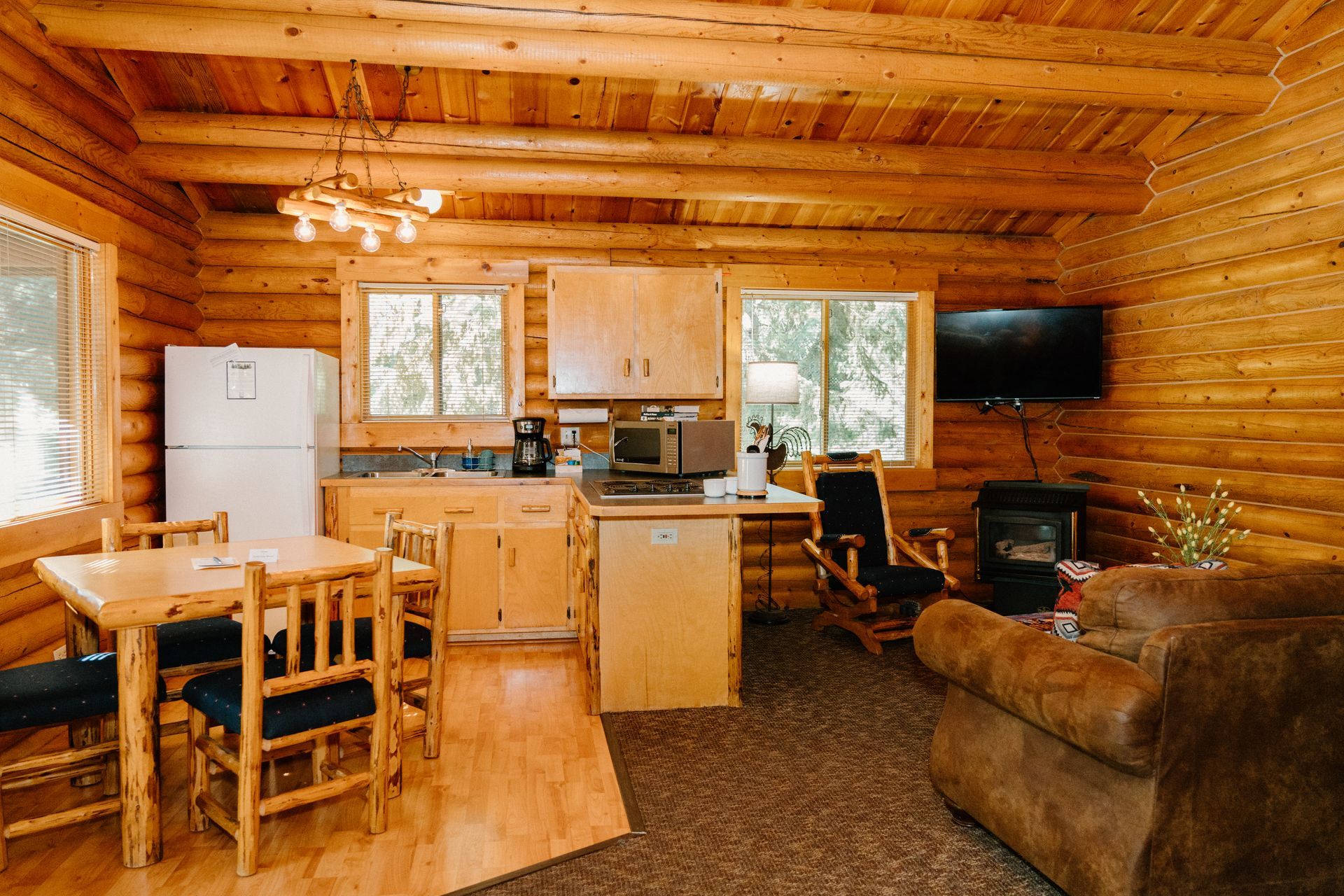 A log cabin with a kitchen , dining room , living room and television.