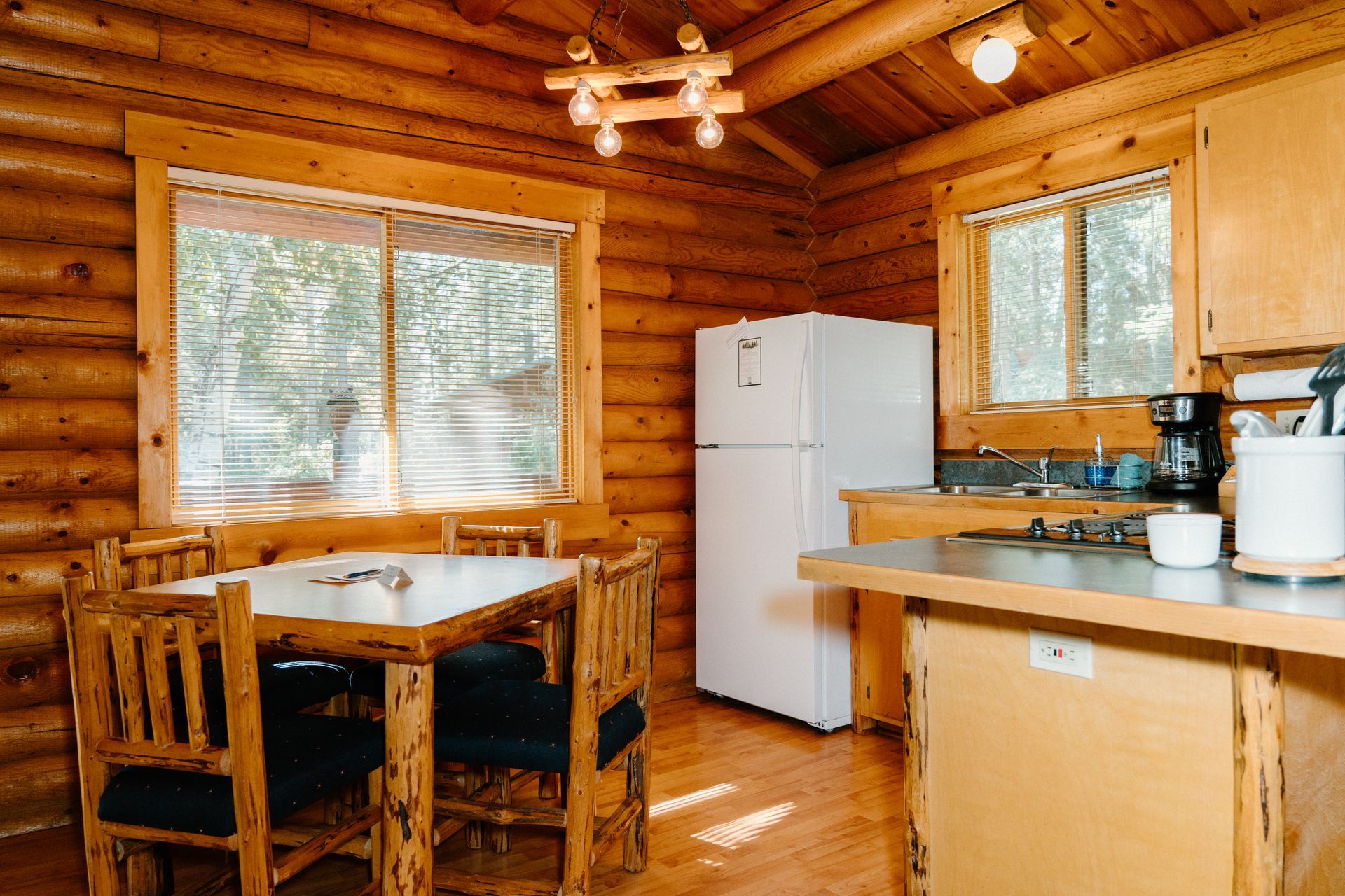 A kitchen in a log cabin with a table and chairs and a refrigerator.