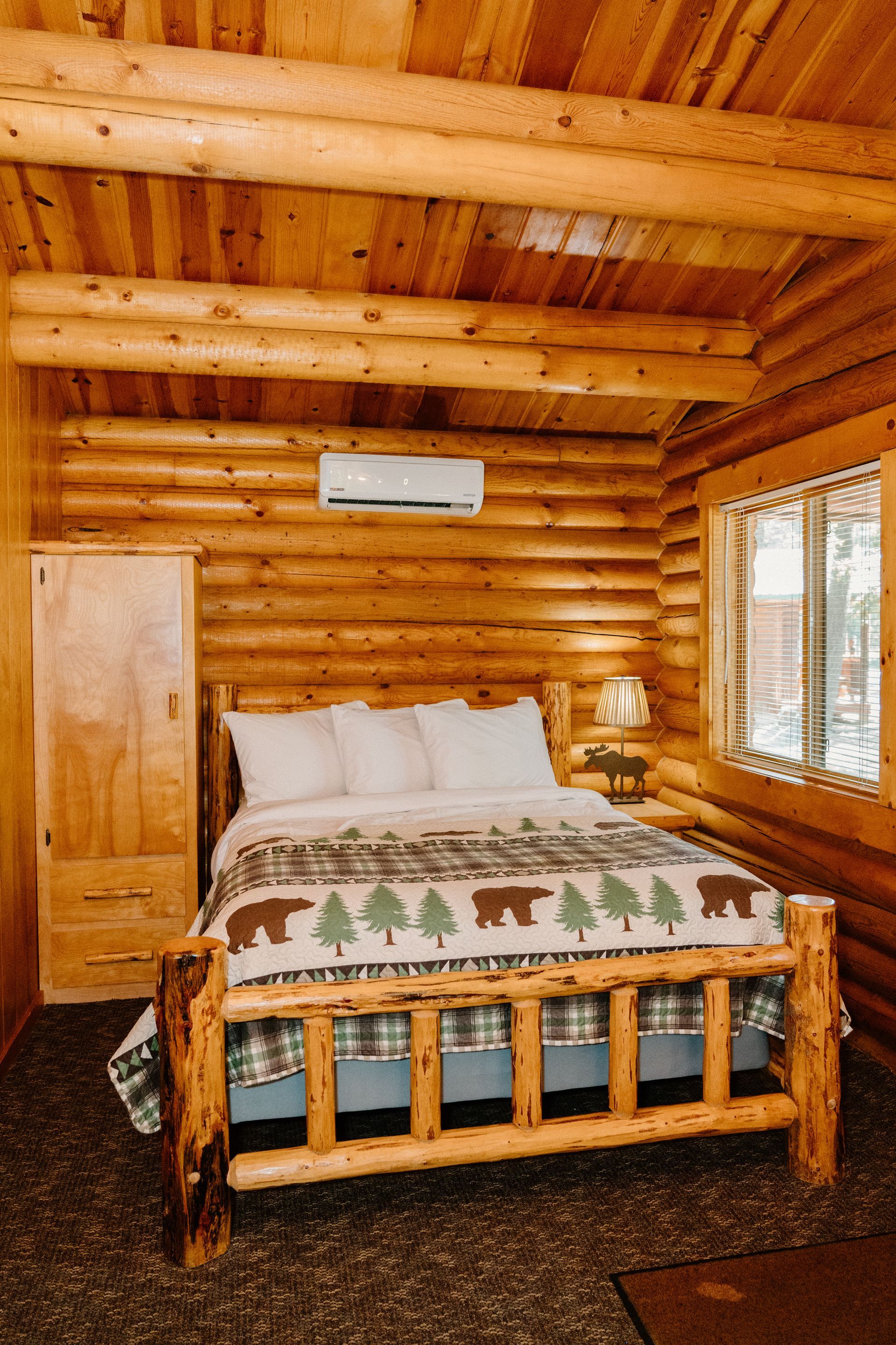 A bedroom in a log cabin with a bed and a window.