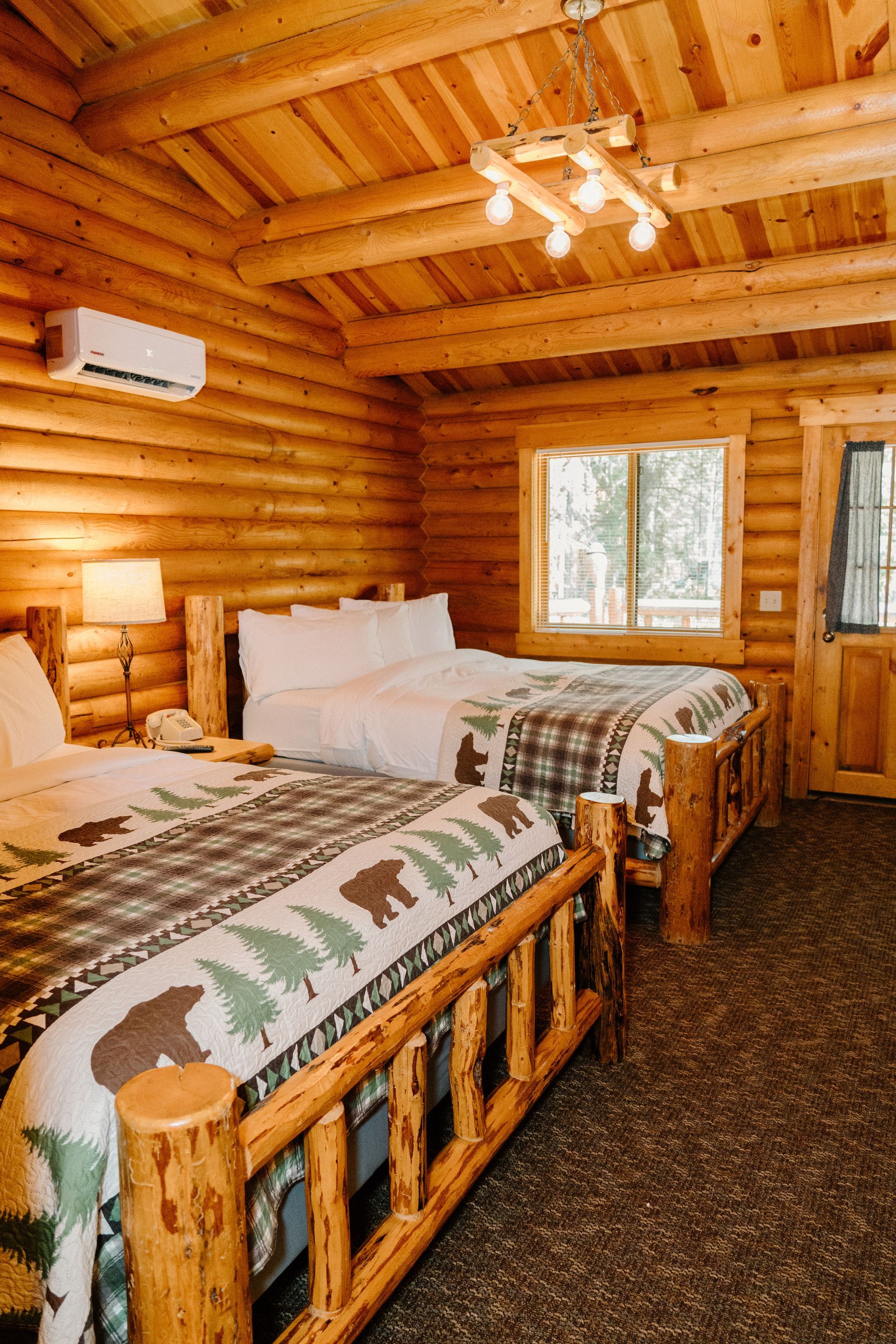 A bedroom in a log cabin with two beds and a chandelier.