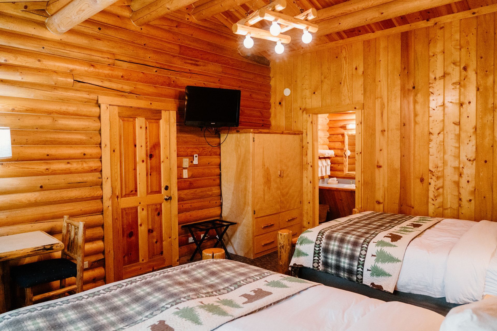 A bedroom in a log cabin with two beds and a television.