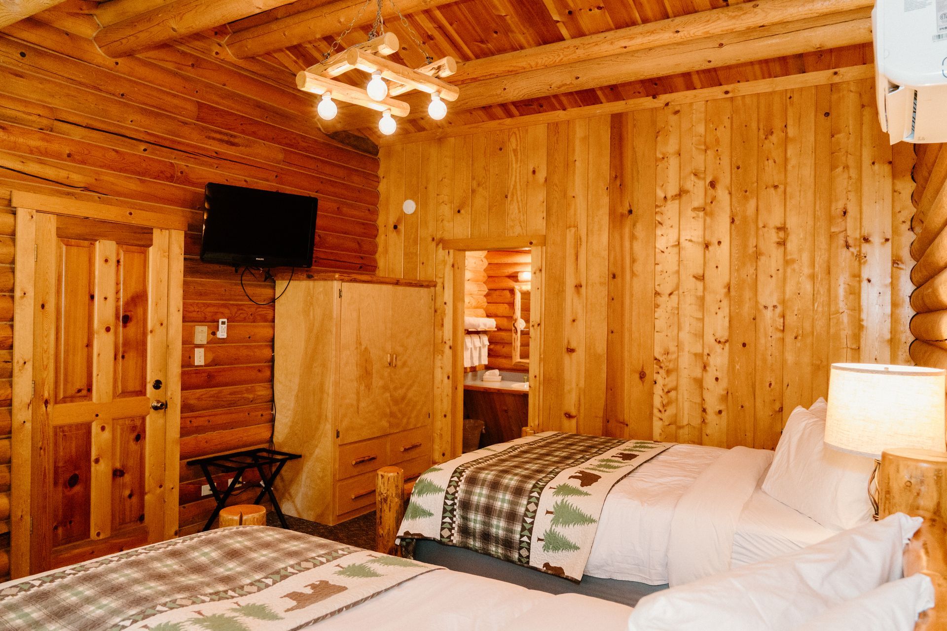 A bedroom in a log cabin with two beds and a flat screen tv.