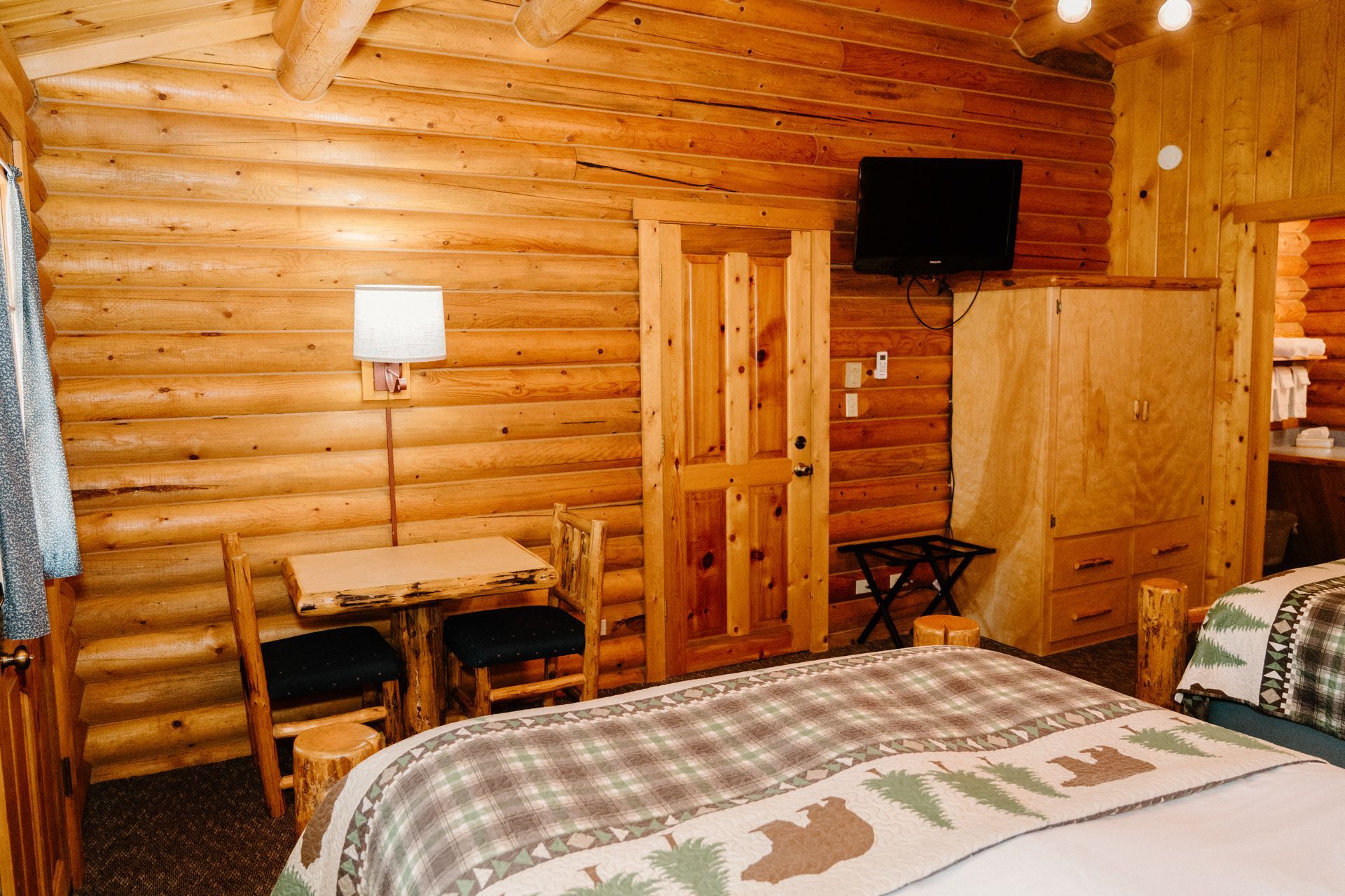 A log cabin with a bed , table , chairs and television.