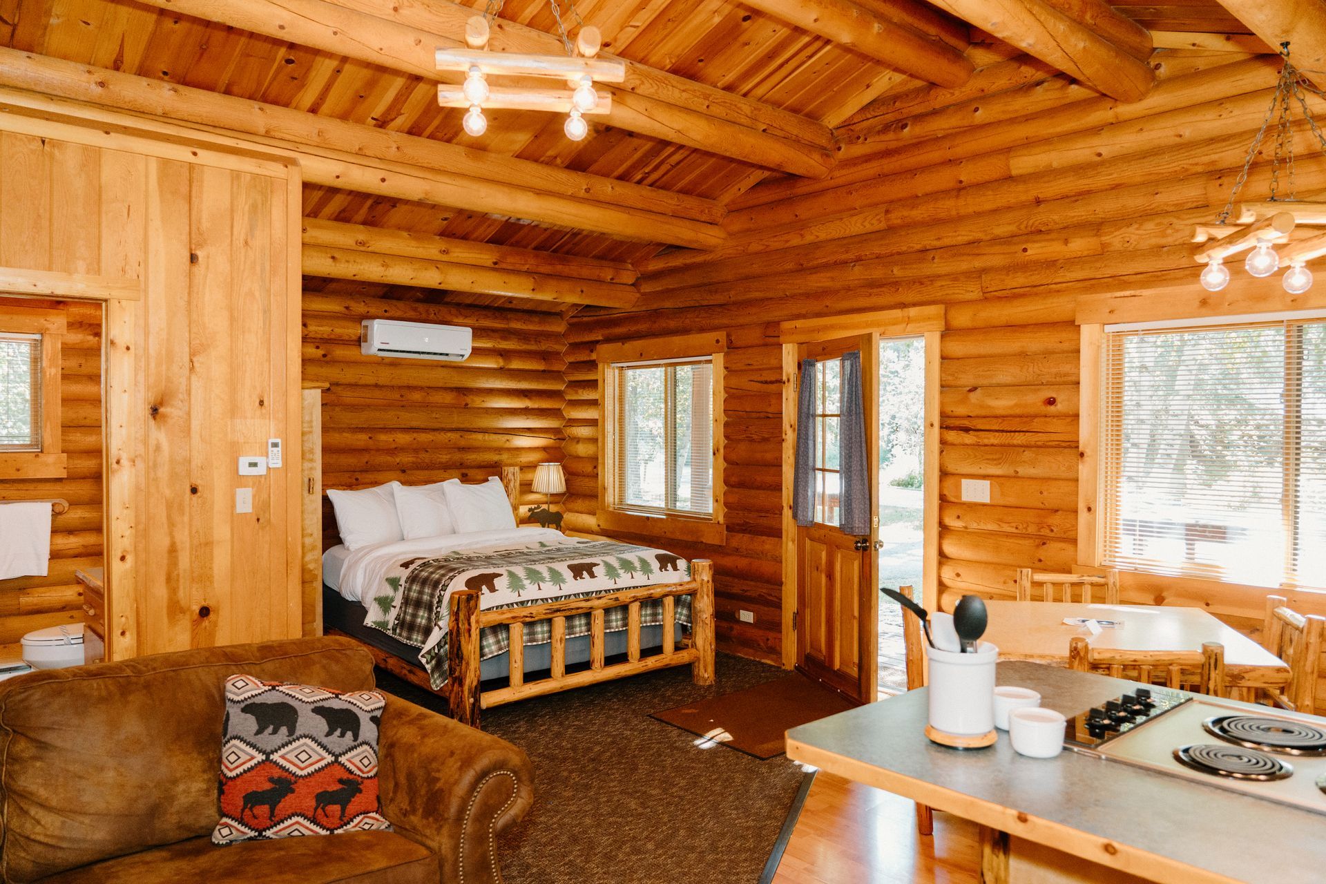 There is a bed in the middle of the room in a log cabin.