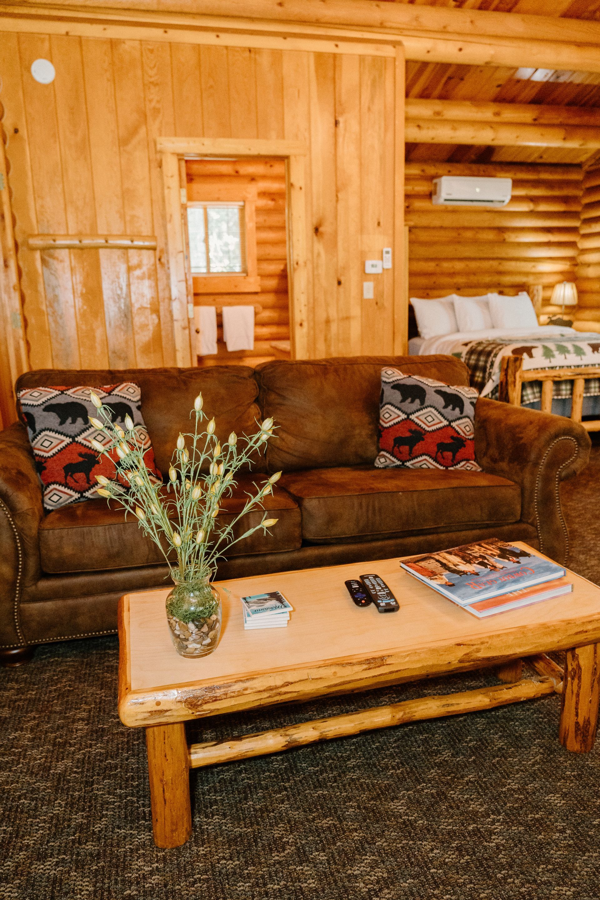 A living room in a log cabin with a couch and a coffee table.