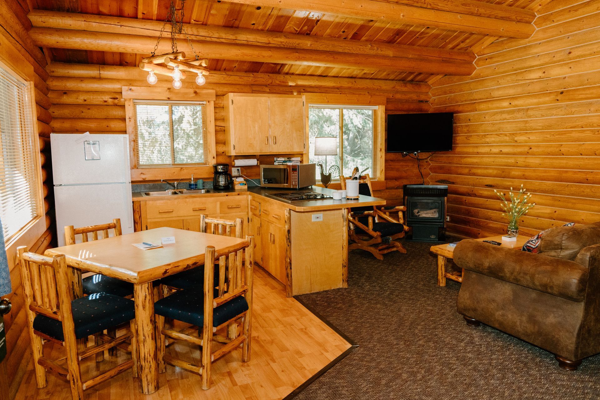 A log cabin with a dining table , chairs , a refrigerator , and a television.