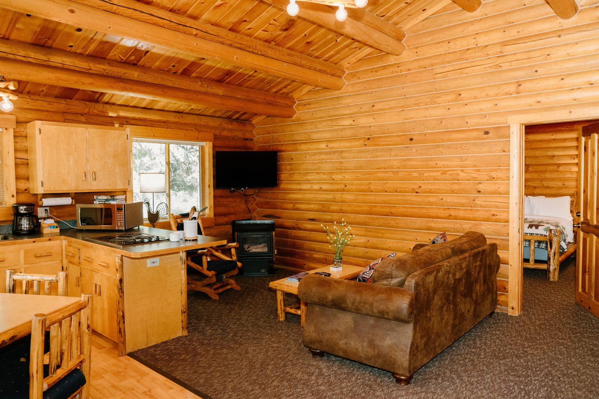 A living room in a log cabin with a couch , chair , table and television.