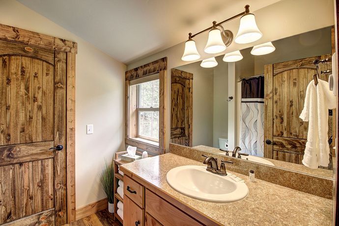 A bathroom with a sink , mirror and wooden doors.