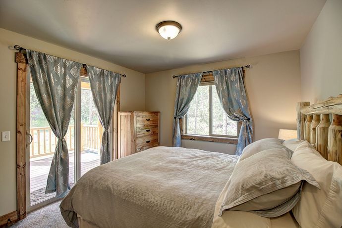 A bedroom with a king size bed and sliding glass doors leading to a deck.