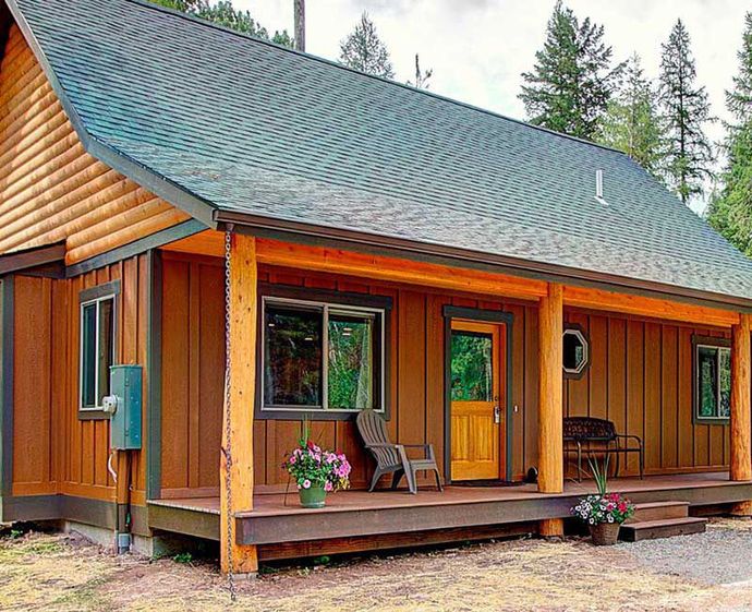 A small log cabin with a porch and chairs on it.