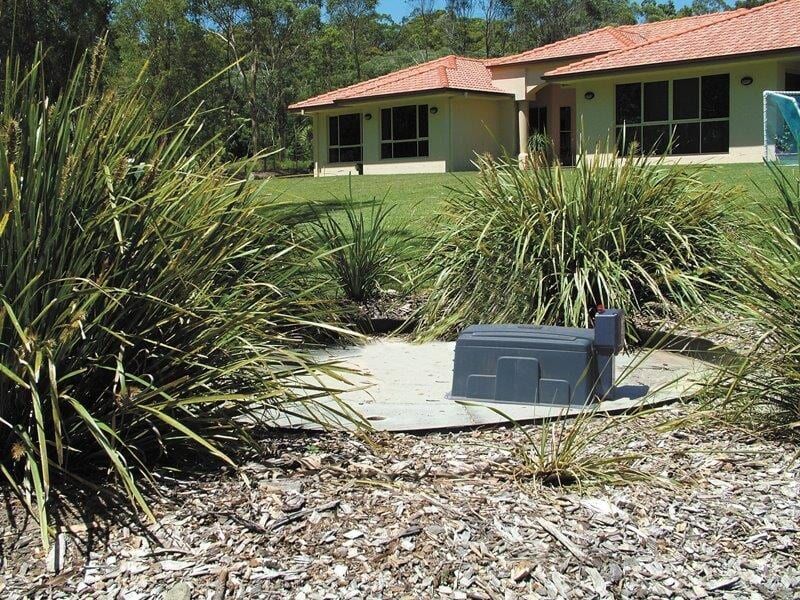 A House With a Red Tile Roof is Surrounded by Tall Grass — Fastcall Group In Herbert, NT