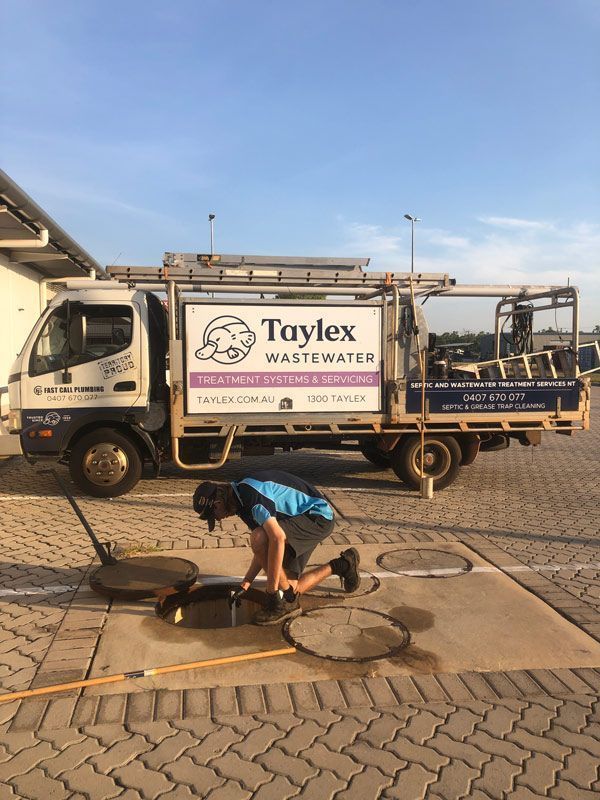 A Man is Kneeling in Front of a Truck That Says Taylex Wastewater — Fastcall Group In Herbert, NT