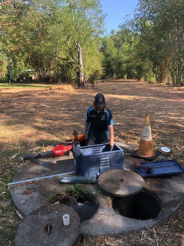 A Man is Working on a Septic Tank in a Field — Fastcall Group In Herbert, NT