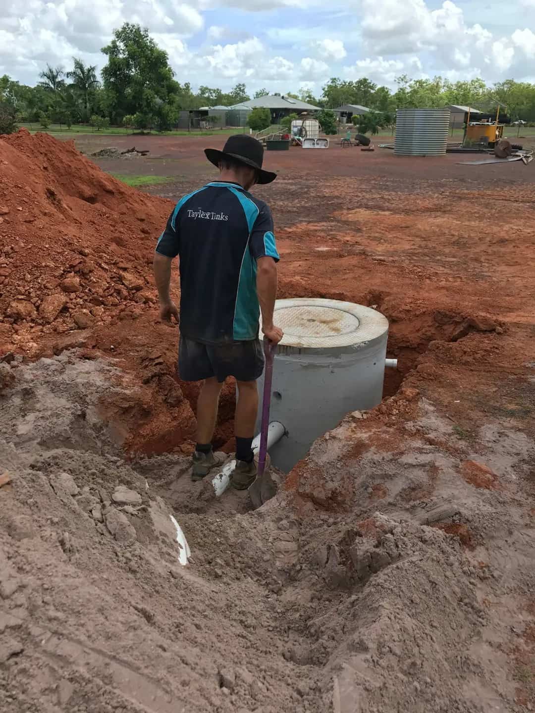 A Man is Standing in the Dirt Next to a Septic Tank — Fastcall Group In Herbert, NT