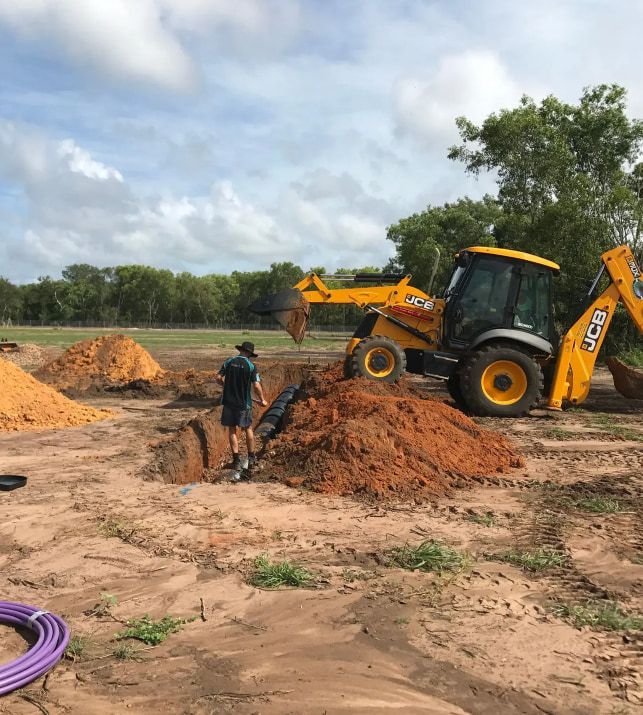 A Man is Digging a Hole in the Dirt Next to a Bulldozer — Fastcall Group In Herbert, NT