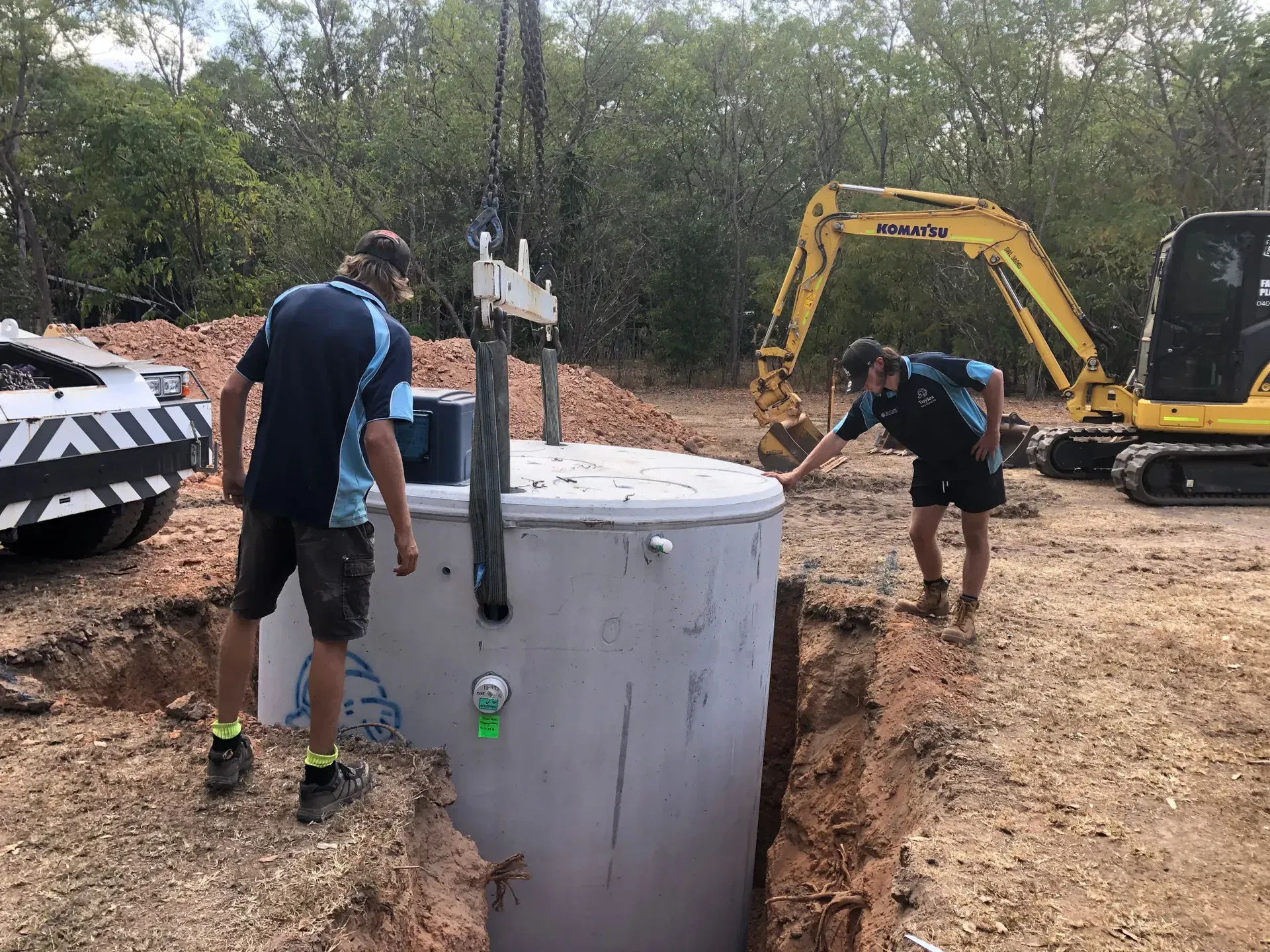 Two Men Are Installing A Septic Tank In The Ground— Fastcall Group In Herbert, NT