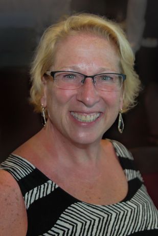a woman wearing glasses and earrings is smiling for the camera