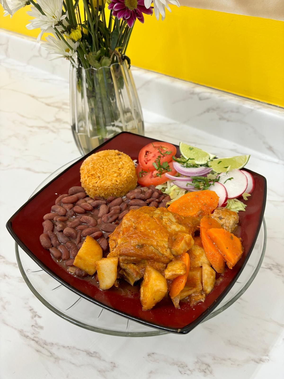 A plate of food with rice , avocado , tomatoes and limes on a table.