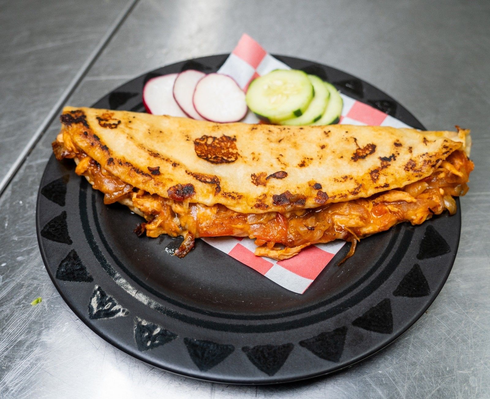 A plate of food with rice , avocado , tomatoes and limes on a table.