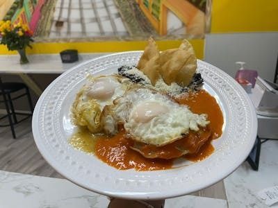 A person is holding a plate of food with eggs and sauce.