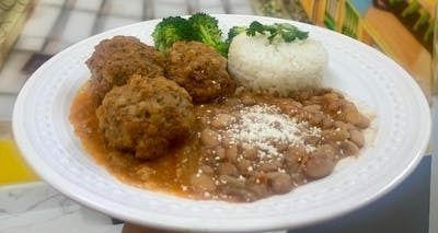 A white plate topped with meatballs , broccoli , rice and beans.