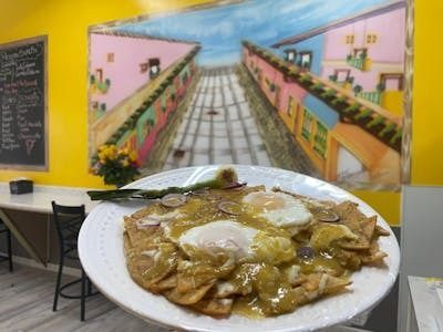 A plate of food is sitting in front of a painting on a wall.