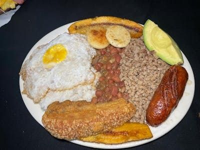 A plate of food with eggs , bananas , beans , rice and avocado on a table.