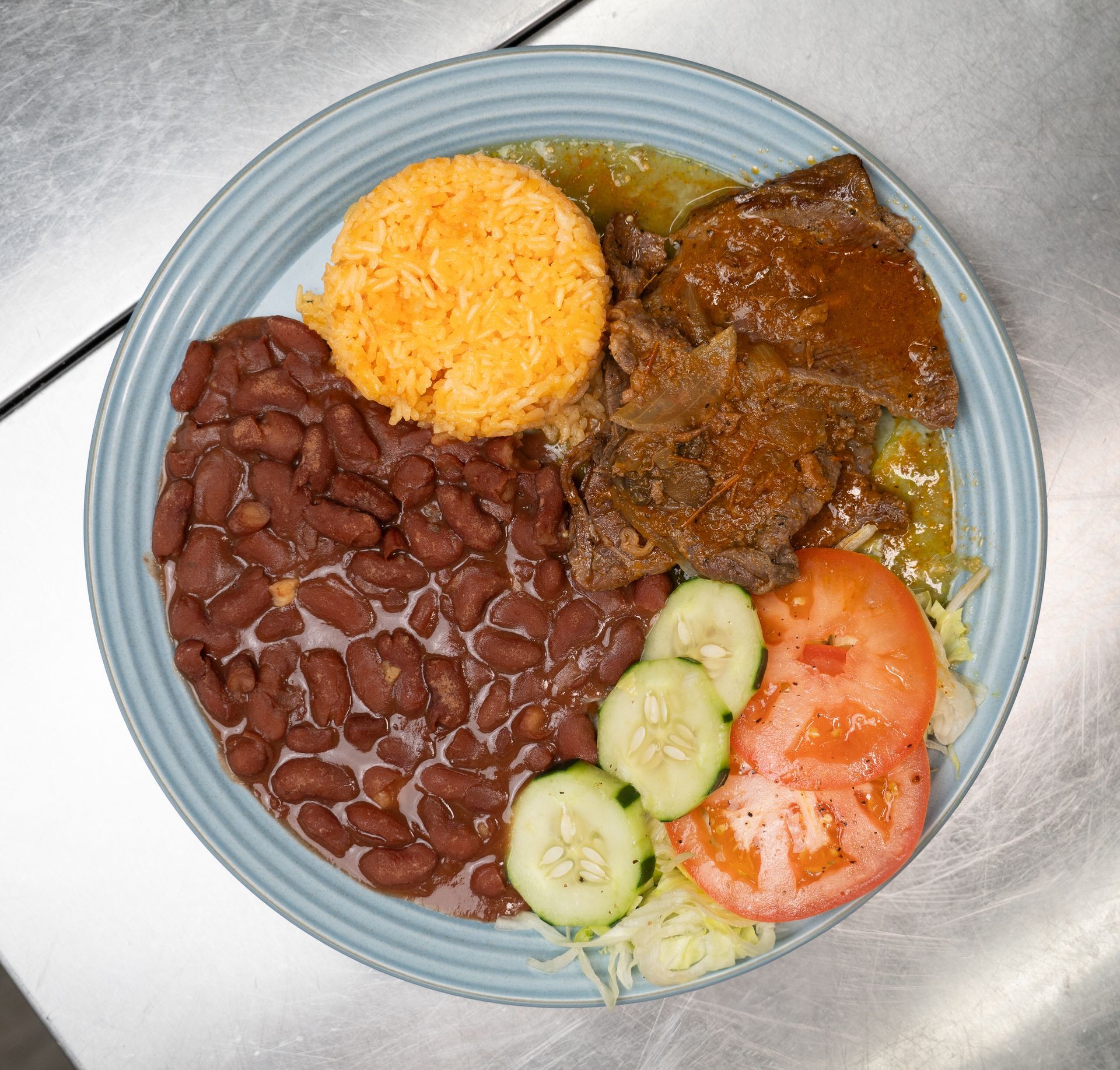 A plate of food with rice , avocado , tomatoes and limes on a table.