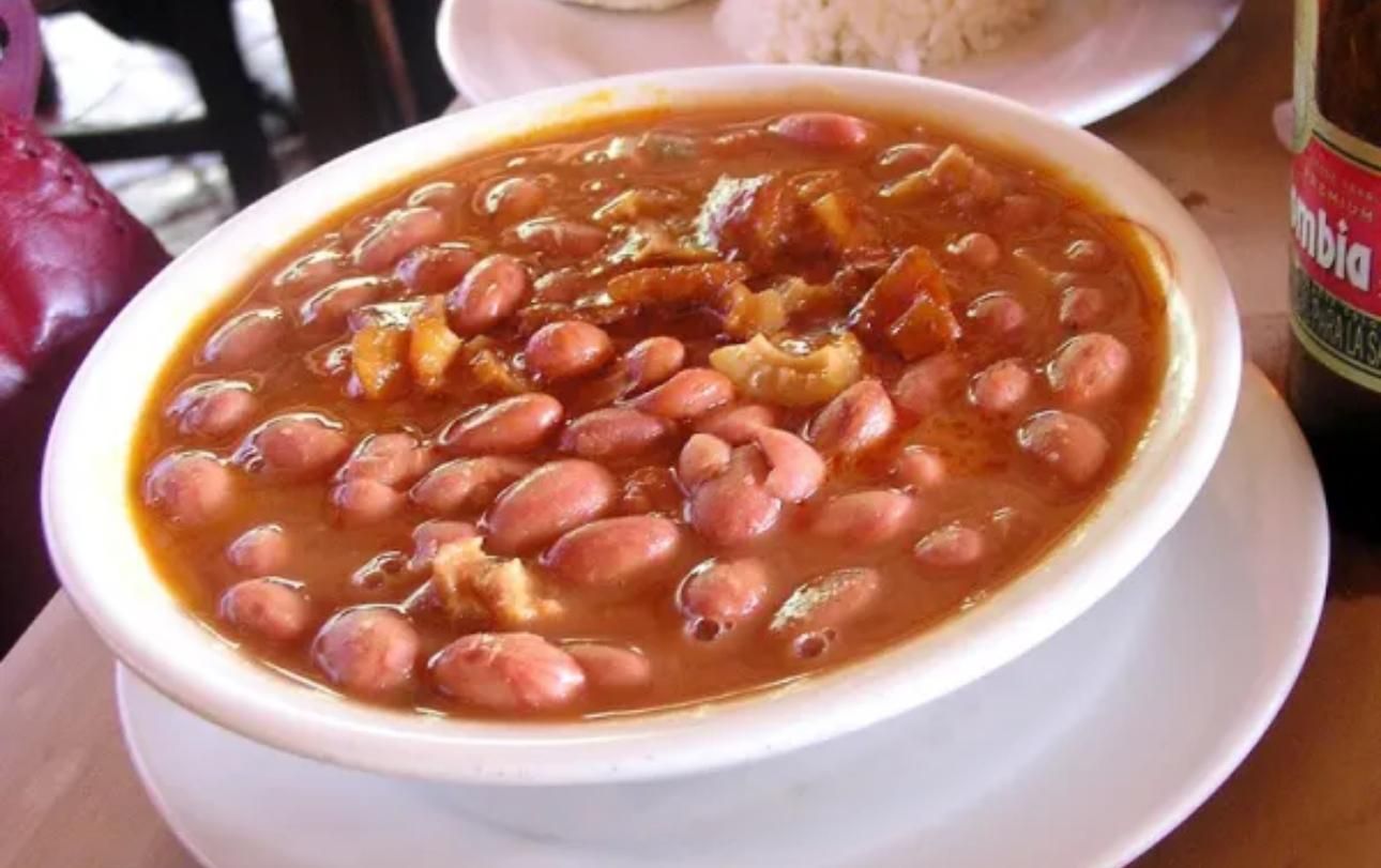 A person is holding a plate of food with eggs and sauce.