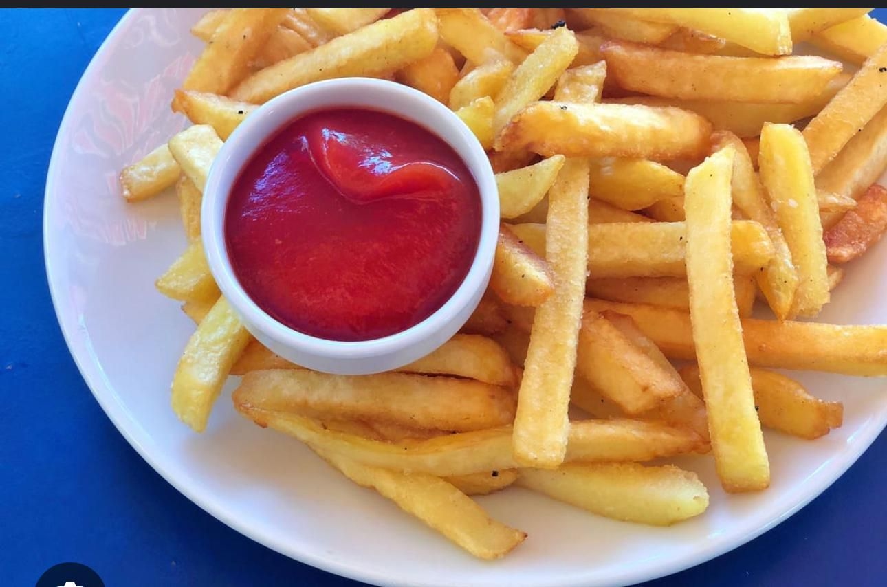 A person is holding a plate of food with eggs and sauce.