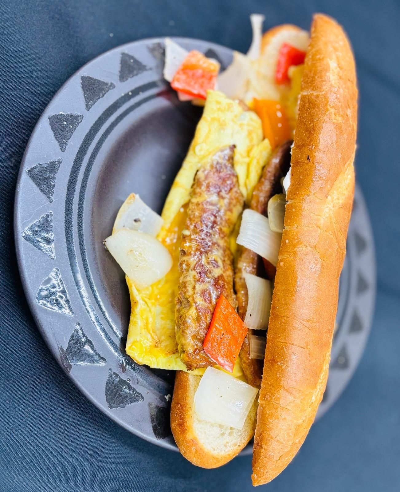 A person is holding a plate of food with eggs and sauce.