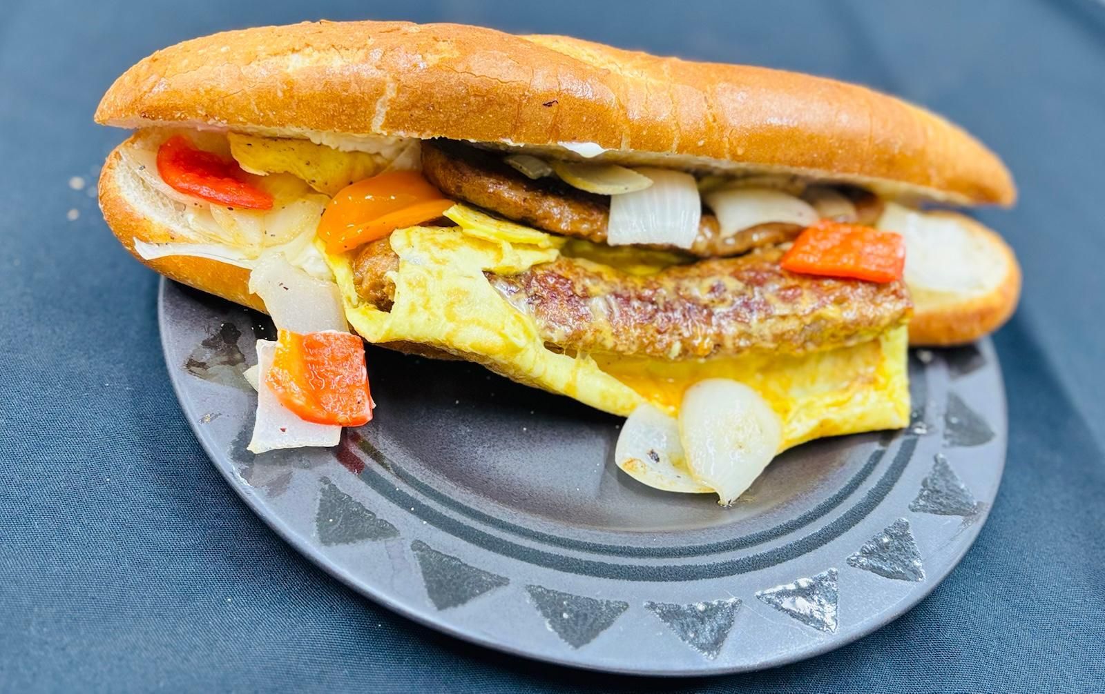A person is holding a plate of food with eggs and sauce.