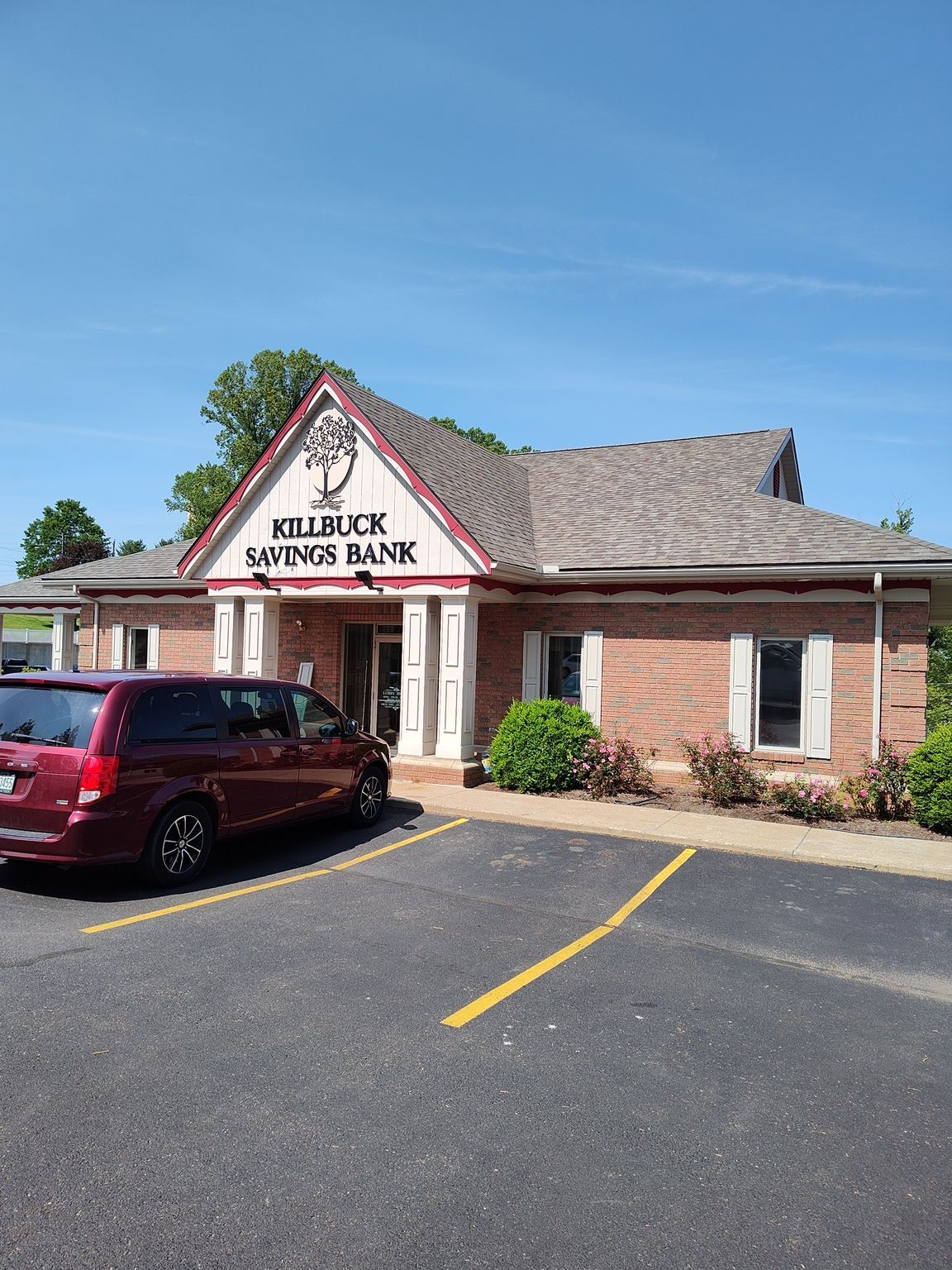 A red van is parked in front of a brick building.