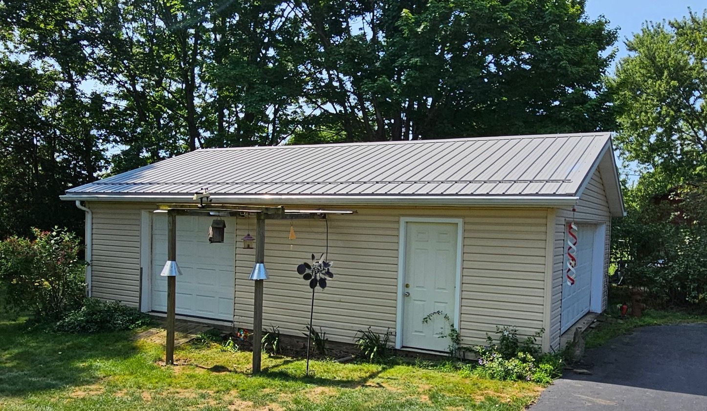 A small white house with a metal roof and a bird feeder in front of it.