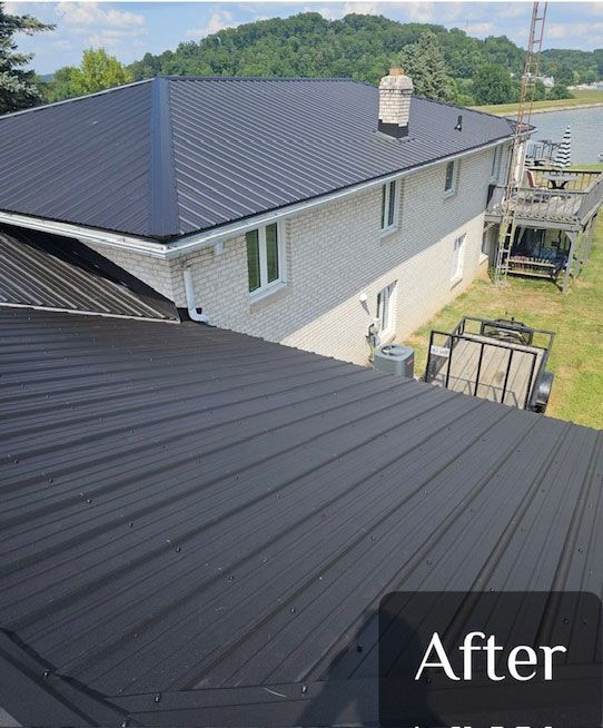 Black metal roof installed on a two-story brick house, sunny day.
