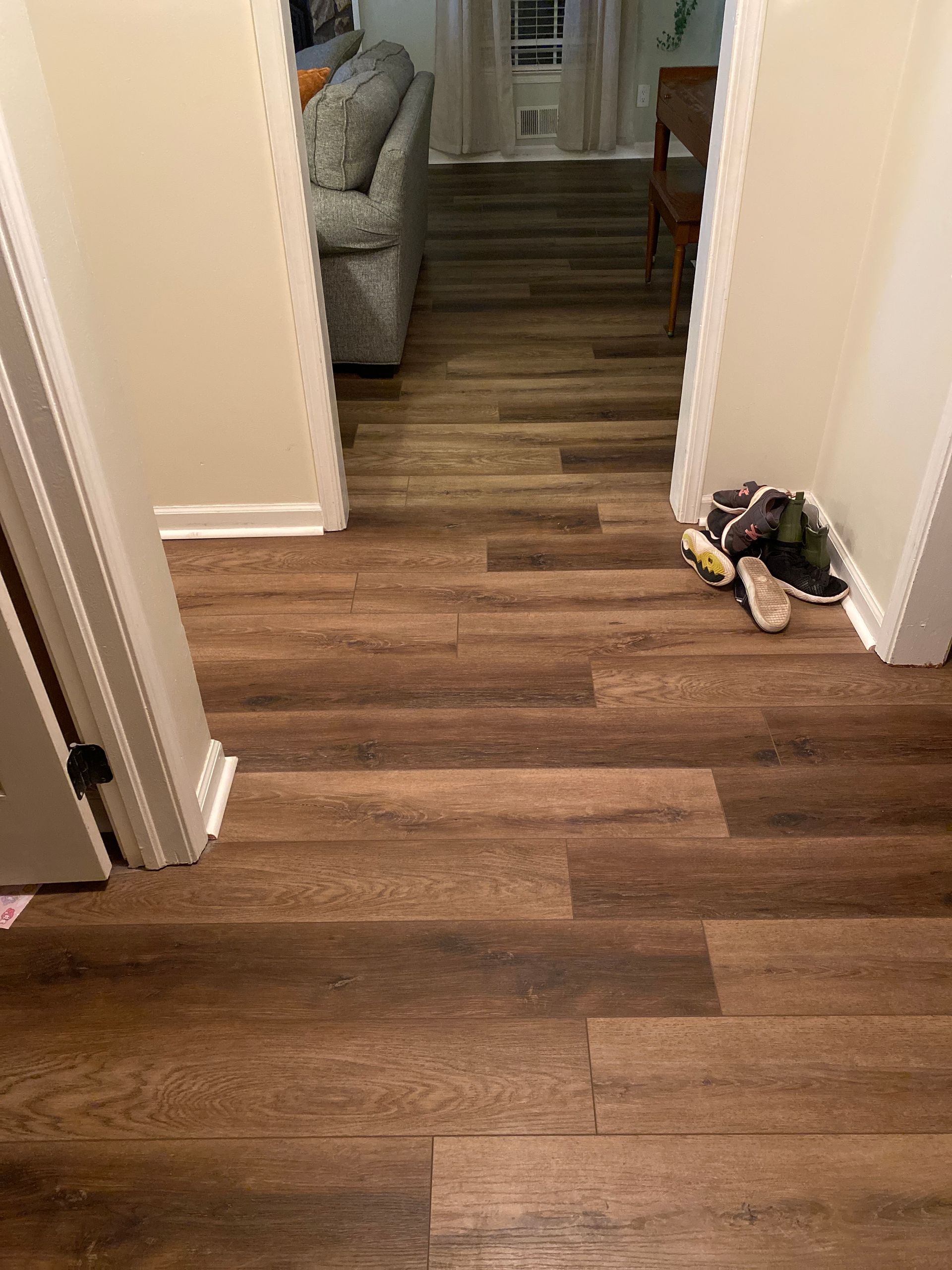A hallway with hardwood floors and a couch in the background.