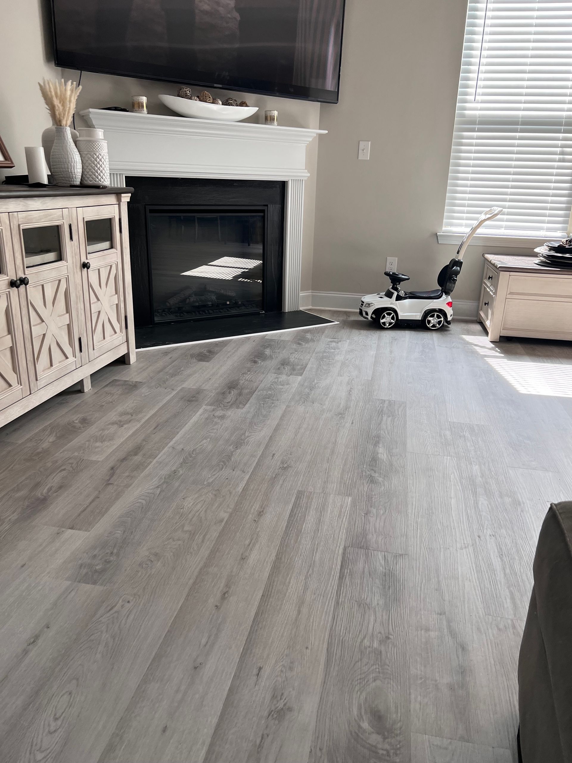 A living room with hardwood floors , a fireplace and a television.