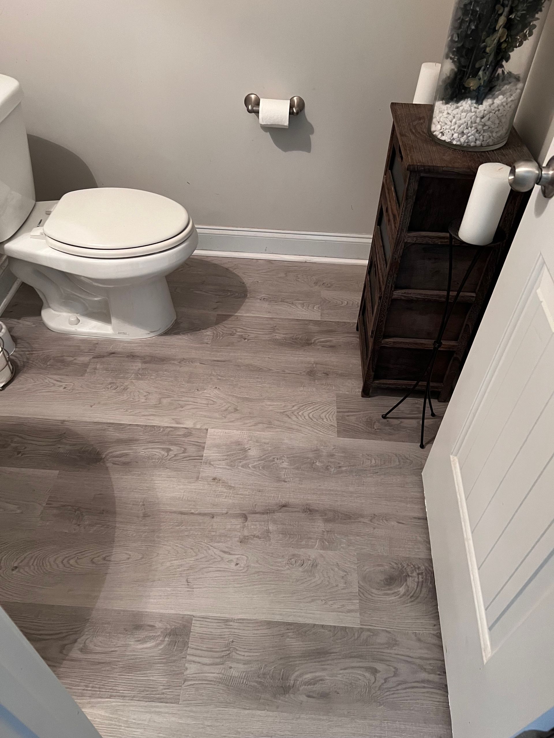 A bathroom with a toilet and a wooden floor.