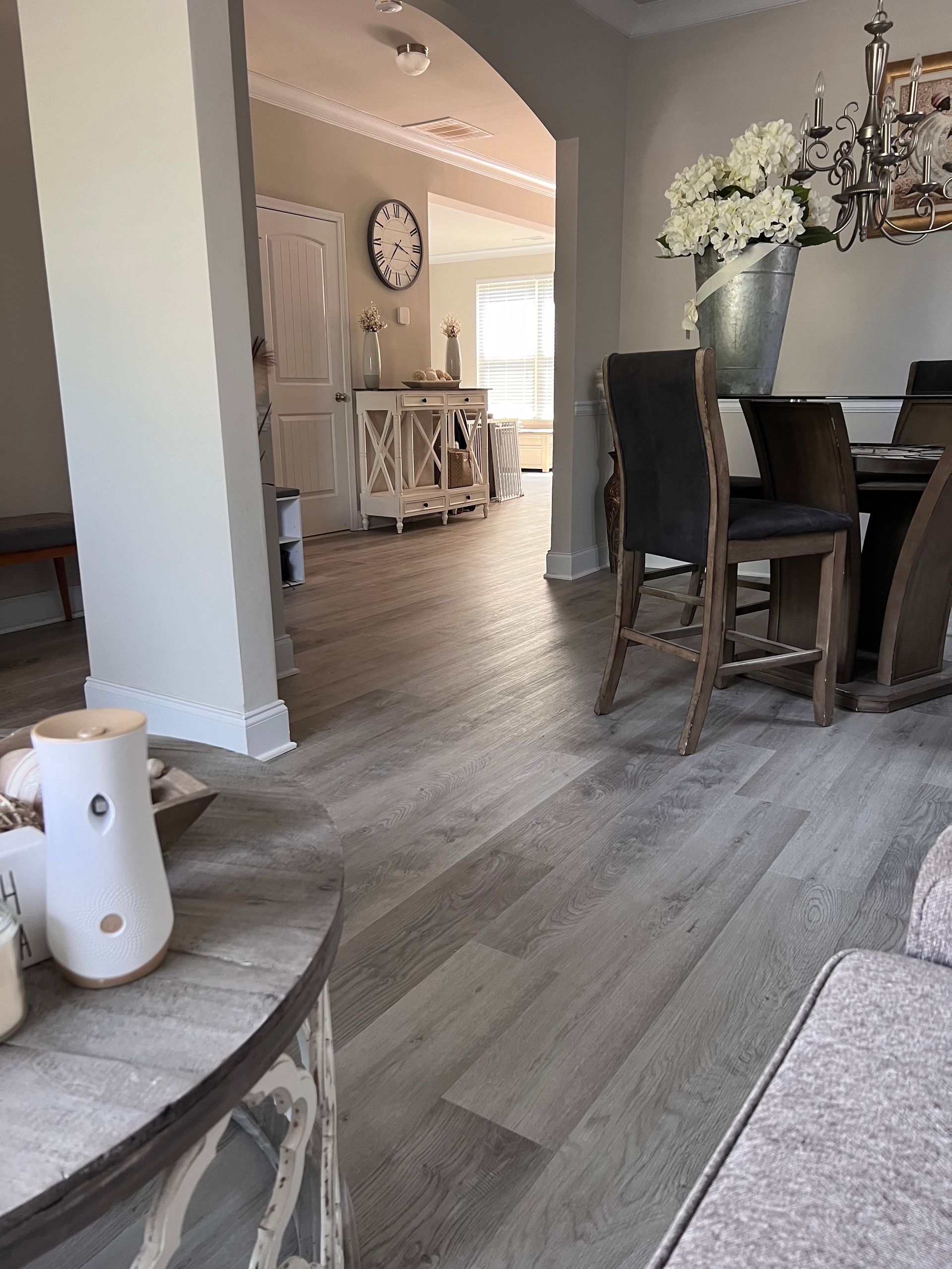 A living room with a table and chairs and a clock on the wall.