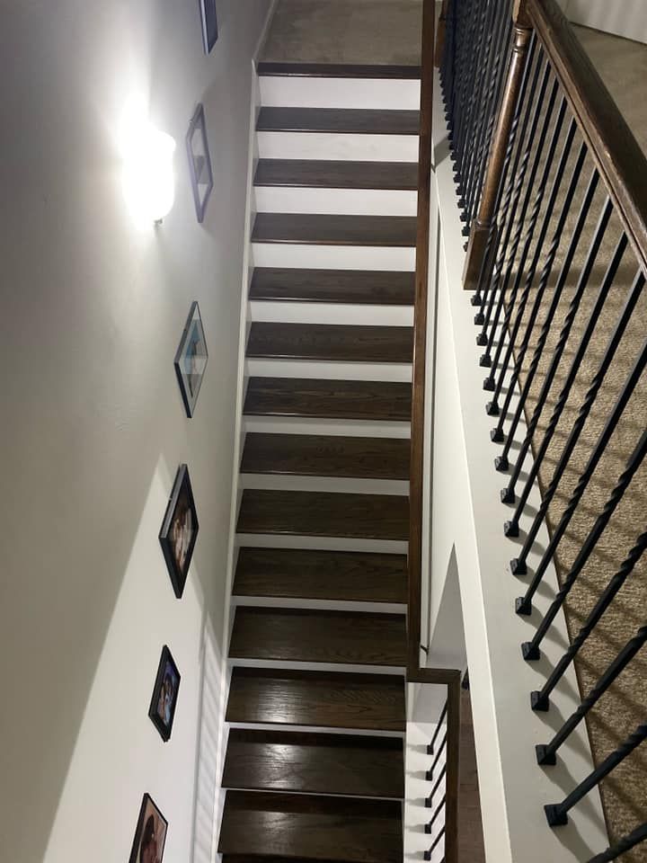 A wooden staircase with a metal railing and pictures on the wall.