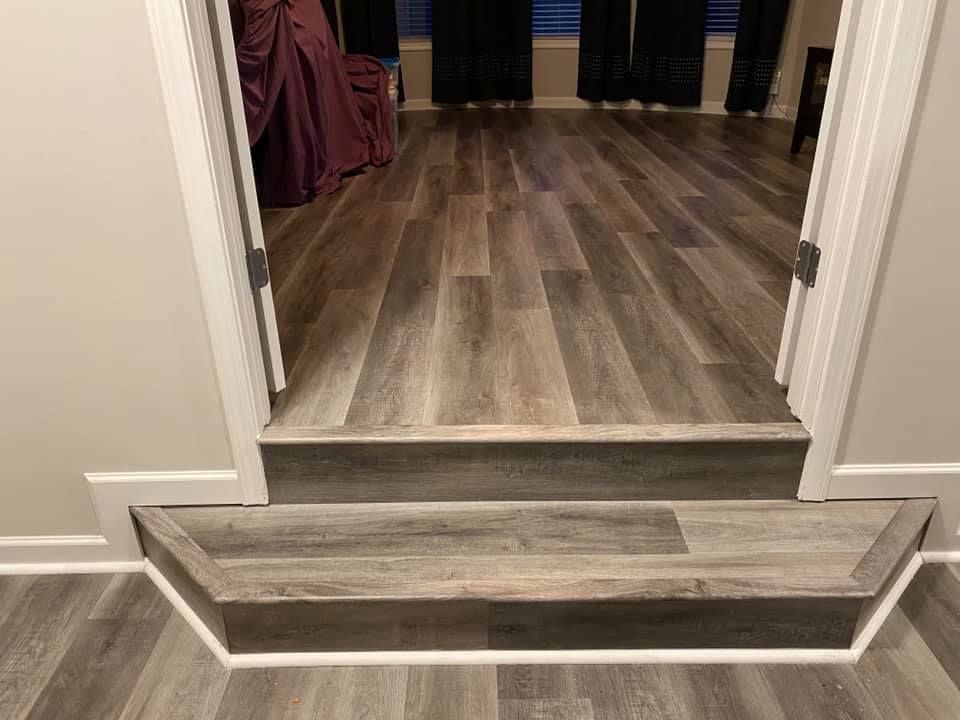 A room with hardwood floors and stairs leading to a bedroom.